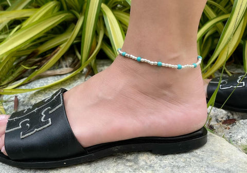 Zoomed-in photo of a model wearing a round beads stackable beach anklet from Hill to Street with black open-toe shoes