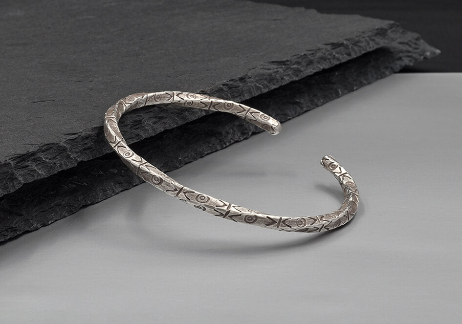 Tribal stamped twisted silver bangle from Hill to Street  seating on a dark stone