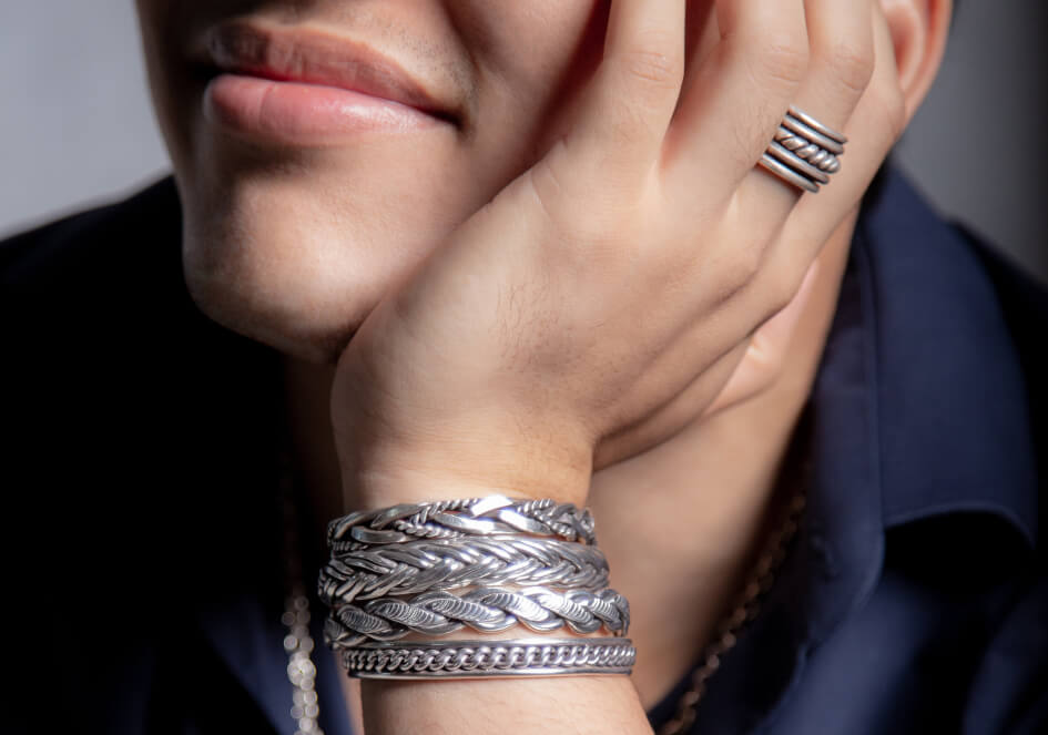 Model wearing a twisted silver band ring and a silver bracelet stack from Hill to Street