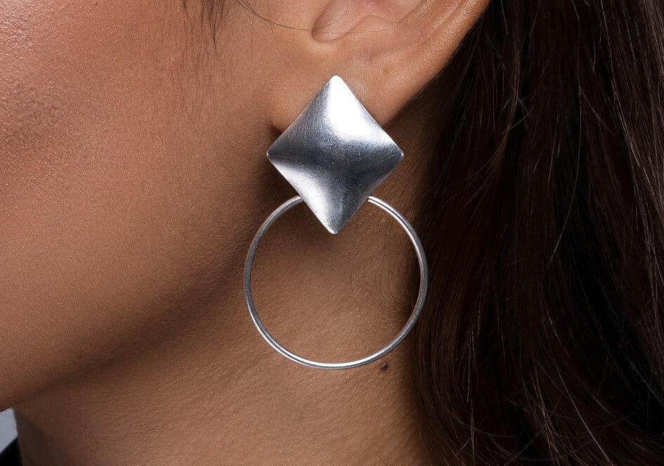 Zoomed-in photo of a model wearing a pair of geometric retro statement stud earrings from Hill to Street