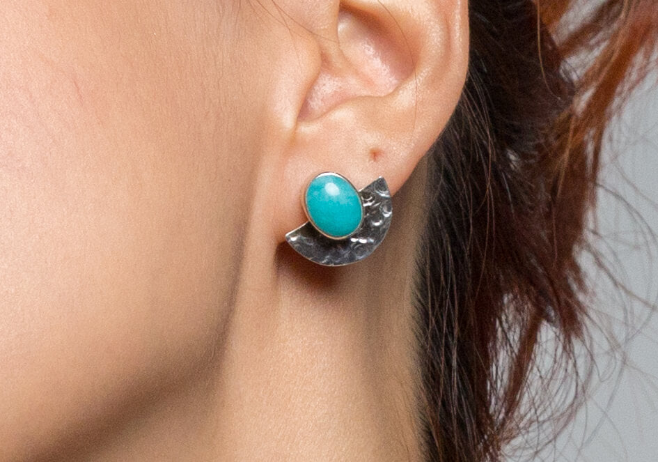 Zoomed-in photo of model wearing a pair of halfmoon sterling silver stud earrings with amazonite from Hill to Street
