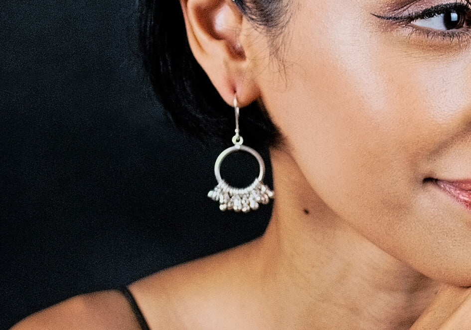 Zoom-in on model wearing a pair of multi-ball silver drop earrings from Hill to Street