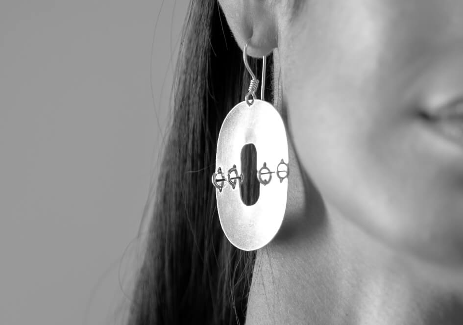 Black and white photo of model wearing oval cut-out silver drop earrings from Hill to Street