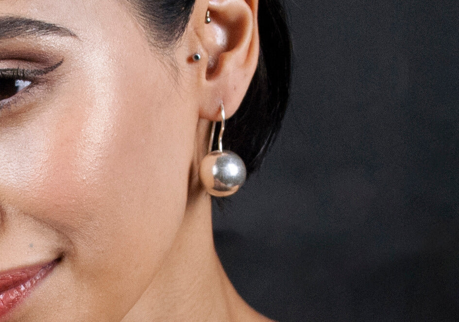 Model wearing silver ball drop earrings from Hill to Street