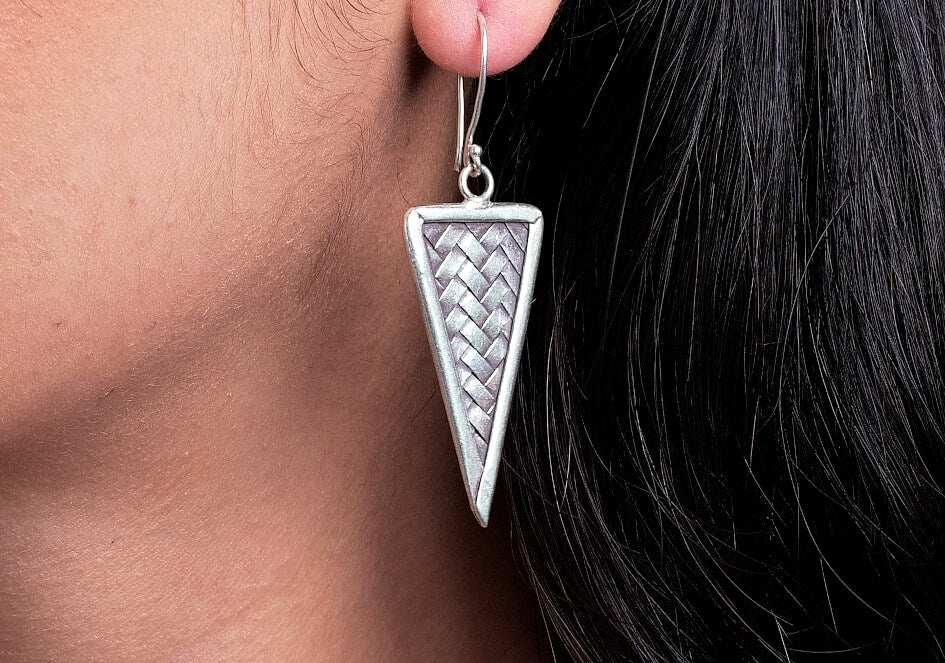 Zoomed-in photo of a model wearing a pair of weave triangle silver drop earrings from Hill to Street